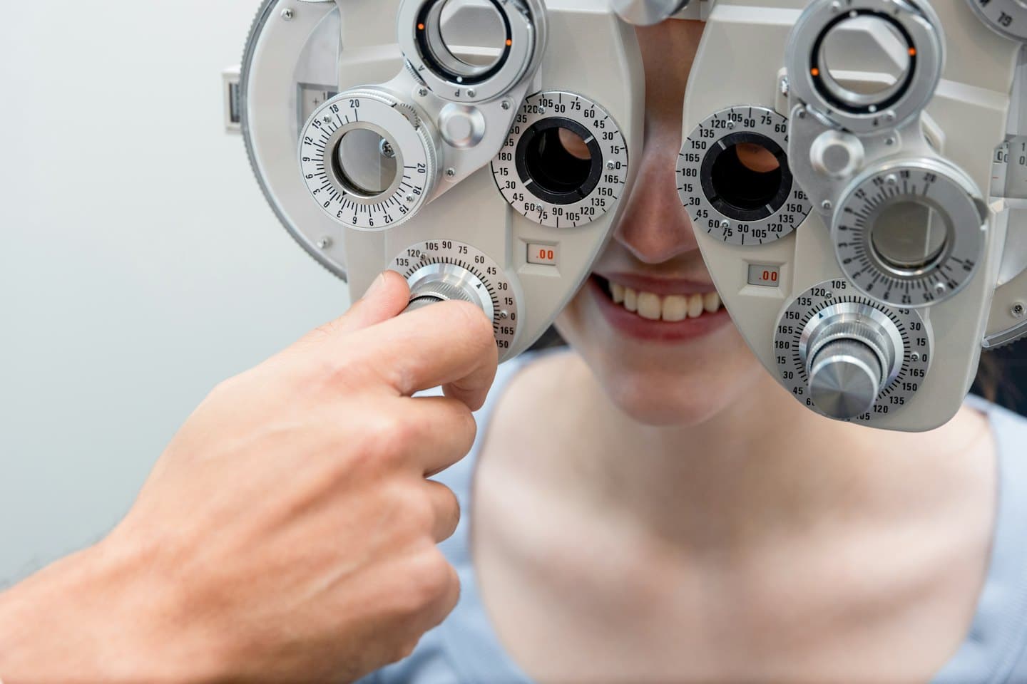 Optometrist adjusts a phoropter during a patient's eye exam.